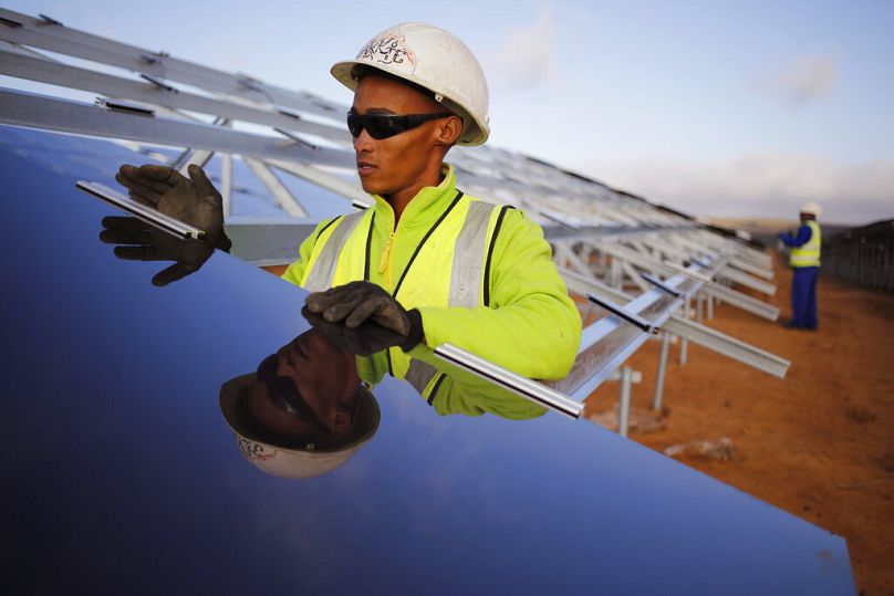 A worker installs a solar panel at a photovoltaic solar park situated on the outskirts of the coastal town of Lamberts Bay, South Africa, March 2016