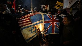 Iráni tüntetők brit, amerikai és izraeli zászlók ábrázolásait égetik el tüntetés közben, a brit nagykövetség előtt Teheránban, Iránban, 2024\. január 12-én, pénteken. 