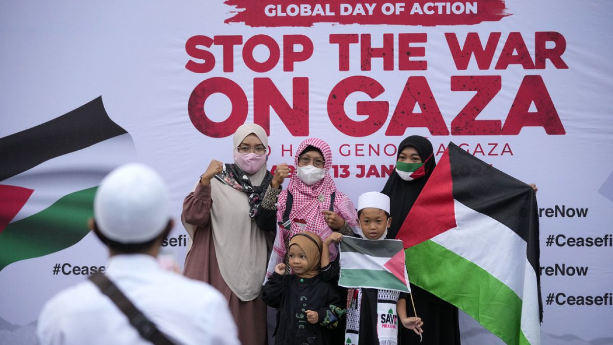 صورة لعائلة على خلفية رسالة تطالب بإنهاء الحرب على غزة خلال مسيرة لدعم الفلسطينيين خارج السفارة الأمريكية في جاكرتا، إندونيسيا، 13 يناير 2024.