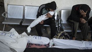 فلسطيني يحمل جثمان طفل راح ضحية القصف الإسرائيلي على منزله