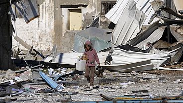 A Palestinian child walks past factories destroyed in the Israeli bombardment of the Gaza Strip in Deir al Balah 