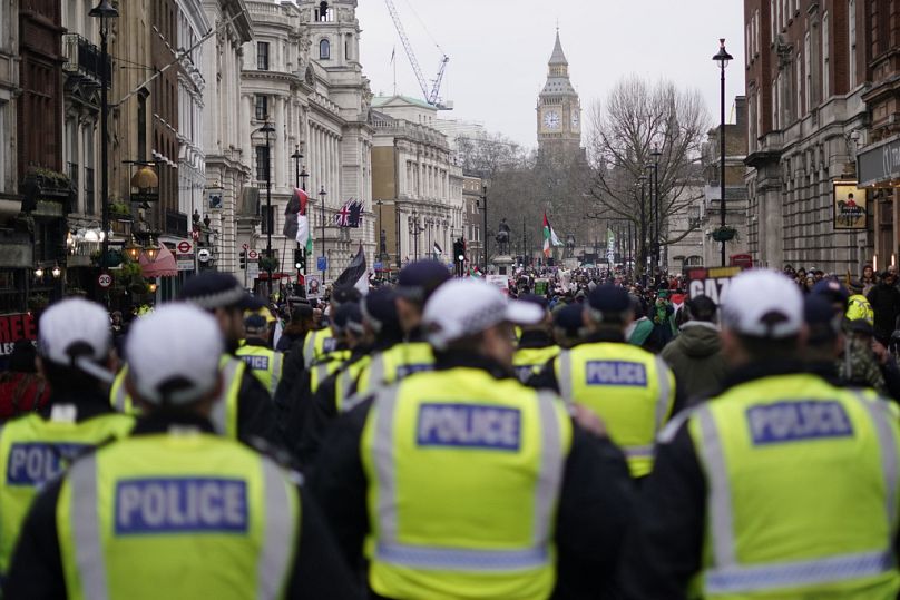 Police follow the march as protesters hold up banners, flags and placards during a demonstration in support of Palestinian people in Gaza, in London, Saturday, Jan. 13, 2024