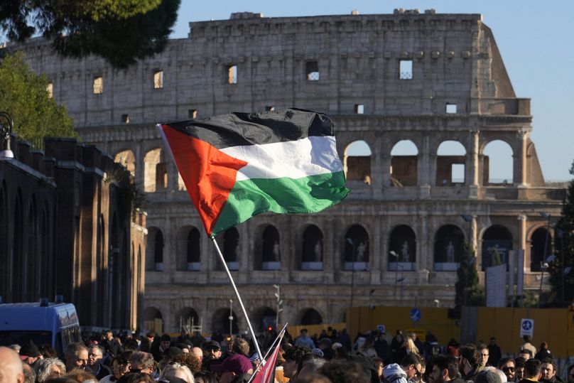 A Palestinian flag is waved in front of the Colosseum, during a rally in support of the Palestinians in Rome, 13 January 2024.