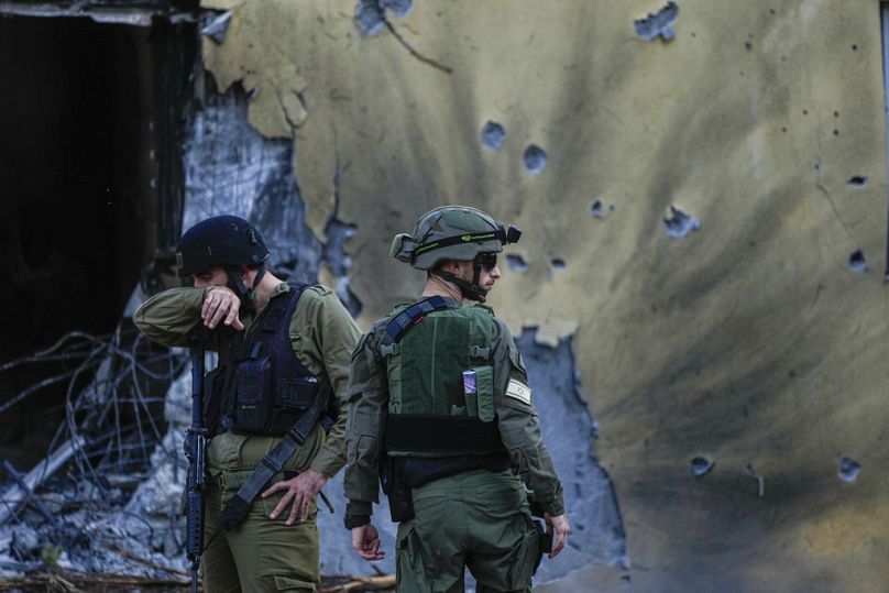 Israeli soldiers walk past houses destroyed by Hamas militants in Kibbutz Be'eri, Israel in October