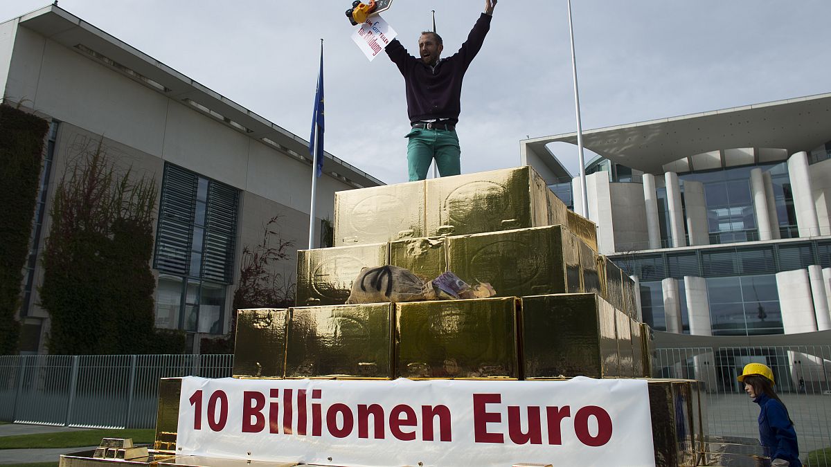 Egy tüntető kiabál egy hamis aranypiramis tetejéről a vagyon újraelosztásáért tartott tüntetésen a berlini kancellária előtt 2012. szeptember 25-én