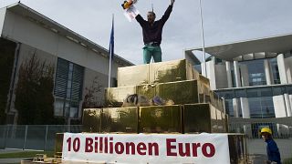 Egy tüntető kiabál egy hamis aranypiramis tetejéről a vagyon újraelosztásáért tartott tüntetésen a berlini kancellária előtt 2012. szeptember 25-én
