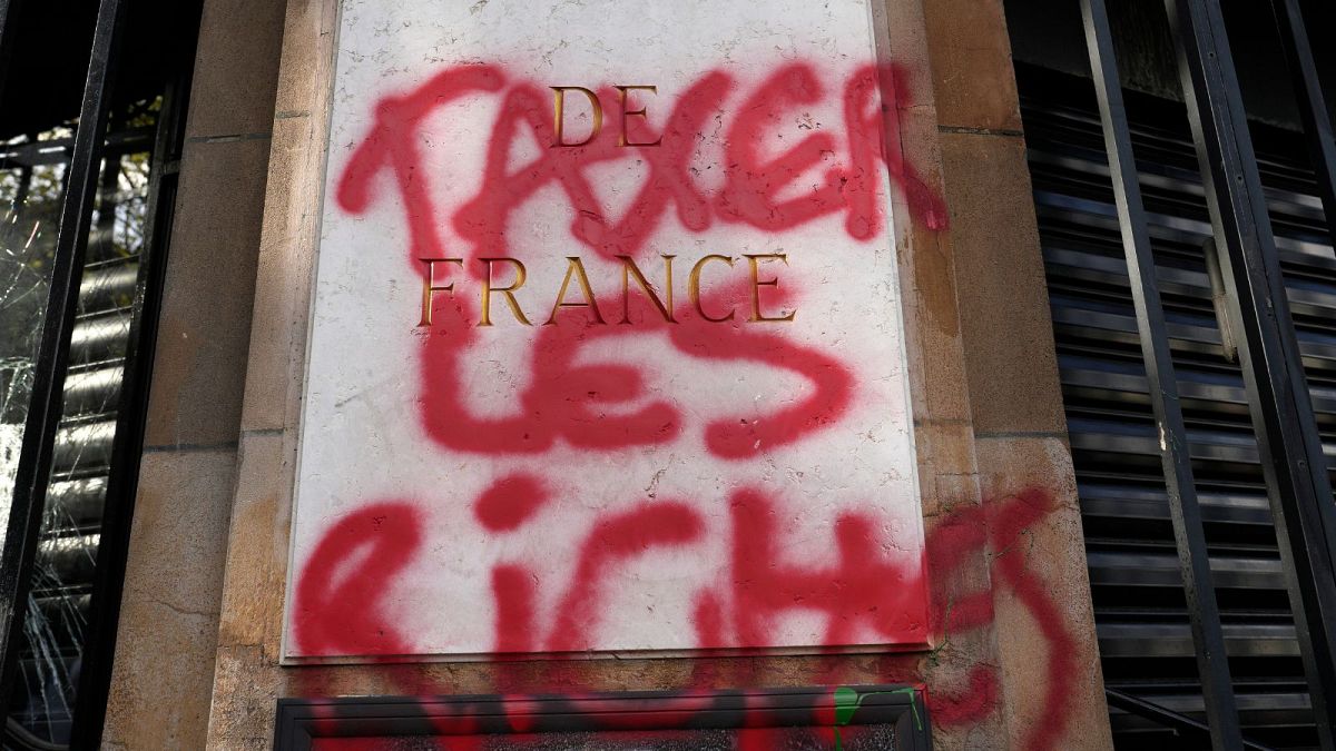 Um graffiti com a inscrição "Taxar os ricos" na fachada do Banco Nacional Francês durante uma manifestação na quinta-feira, 13 de abril de 2023, em Paris.