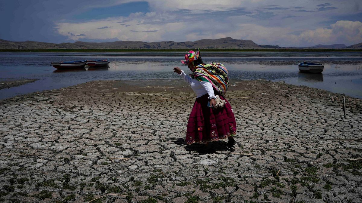 Uma mulher caminha numa parte seca do Lago Titicaca em Coata, Peru, a 29 de novembro de 2023, durante uma onda de calor. 
