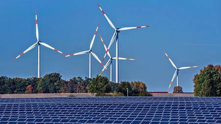 Wind turbines turn behind a solar farm in Rapshagen, Germany, October 2021. 