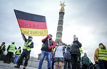 Bauern halten eine Fahne mit der Aufschrift "Unser Land zuerst" in die Höhe, während sie vor der Siegessäule in Berlin protestieren, Montag. Jan. 15, 2024.