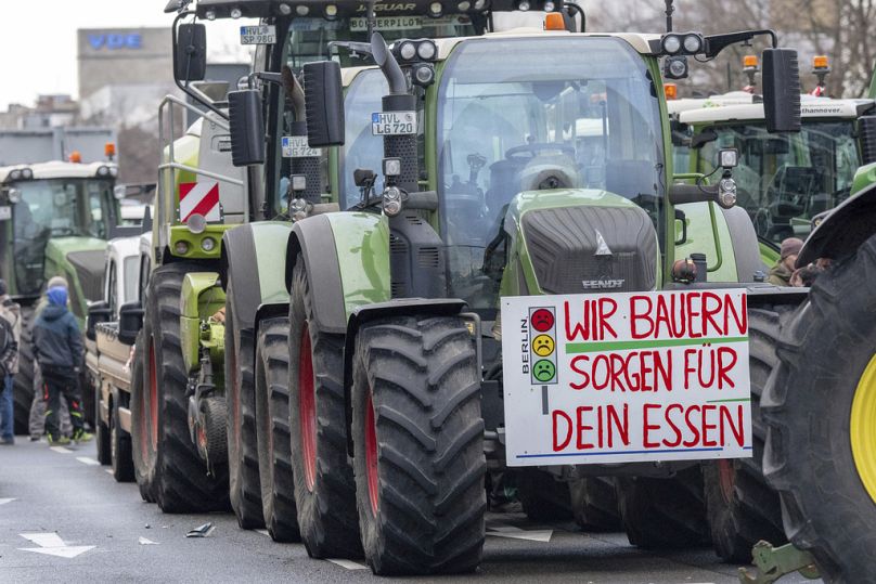 A sign in German saying "We farmers take care of your food" hangs on a tractor parked along Bismarckstraße during the farmers' protest in Berlin, 15 January, 2024.