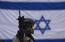 An Israeli border police officer stands guard at  a bus stop in Ra'anana, Israel, Monday, Jan. 15, 2024.