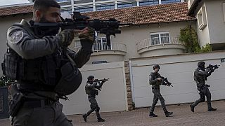 Las fuerzas de seguridad israelíes buscan agresores cerca del lugar de un mortal atropello y apuñalamiento en una parada de autobús, en Ra'anana, Israel, el lunes 15 de enero.