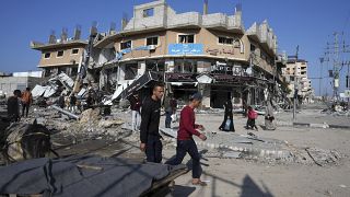 فلسطينيون يمشون وسط الدمار الذي خلفه القصف الإسرائيلي في مخيم النصيرات في غزة. 2024/01/16