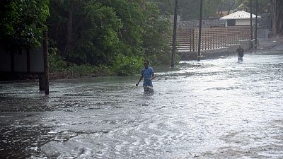 رجل يسير عبر طريق غمرته المياه في ساحل جزيرة موريشيوس في المحيط الهندي يوم الاثنين 20 فبراير 2023.