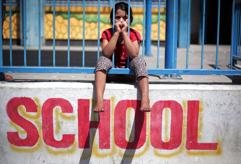 ARCHIVO - Foto del 14 de julio de 2014. Una niña palestina se sienta en la pared de la Nueva Escuela de las Naciones Unidas en Gaza.