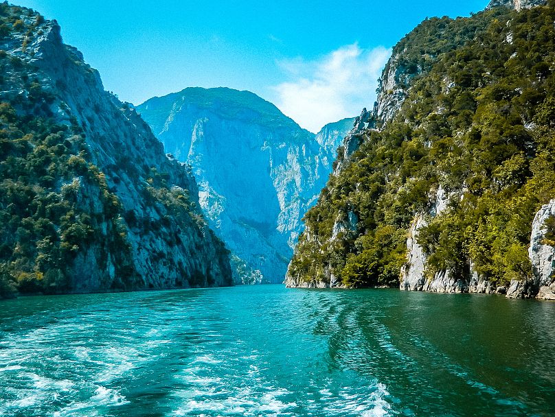 On Lake Komani, the ferry sails through a long gorge of emerald water flanked by fierce rock faces.