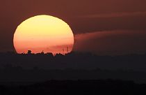 The sun sets behind the buildings in the Gaza Strip as seen from southern Israel, Tuesday, Jan. 16, 2024.