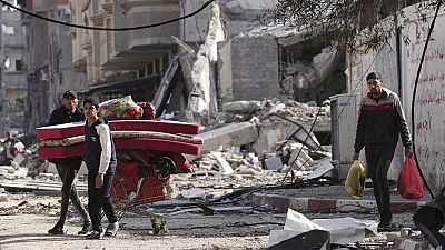 Palestinians walk through destruction by the Israeli bombardment in the Nusseirat refugee camp in Gaza Strip (January 2024)