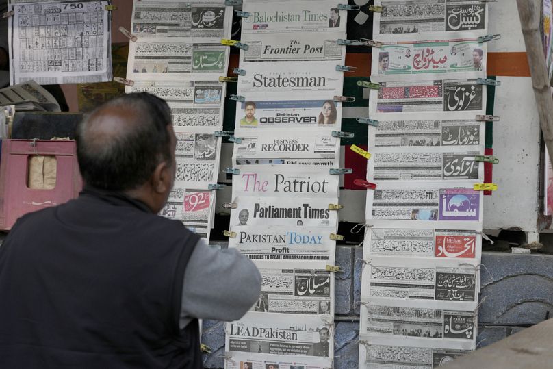 Un pakistanais vérifie les journaux du matin couvrant la première page de l'attaque iranienne, sur un étal à Islamabad, au Pakistan, jeudi