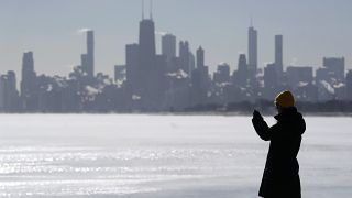 امرأة تلتقط صورًا لبحيرة ميشيغان على شاطئ مونتروز في شيكاغو، الثلاثاء 16 يناير 2024