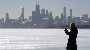 امرأة تلتقط صورًا لبحيرة ميشيغان على شاطئ مونتروز في شيكاغو، الثلاثاء 16 يناير 2024