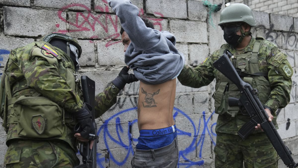 Dos soldados detienen brevemente a un joven para comprobar si tiene tatuajes relacionados con pandilleros, mientras patrullan la zona sur de Quito, Ecuador.