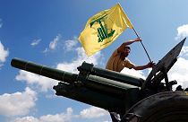 İsrail ile düşük yoğunluklu bir çatışma yürüten İran destekli Hizbullah örgütüne mensup bir savaşçı, örgütün bayrağını dikerken