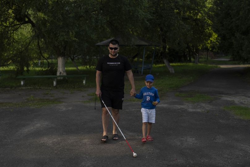 Denys Abdulin, a former Ukrainian soldier blinded in the war, walks with his son, Vadym, near Rivne, July 2023