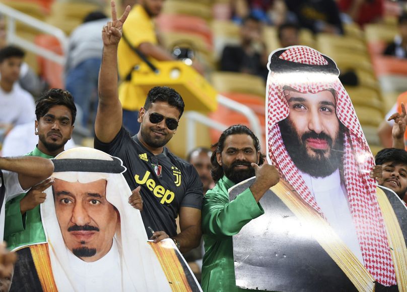 Saudíes mantienen fotos del rey Salman de Arabia Saudita, a la izquierda, y del príncipe heredero saudí Mohammed bin Salman.