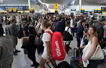 Travellers queue at security at Heathrow Airport in London.