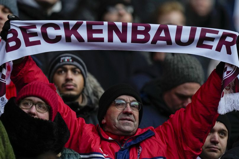A man holds a scarf during a memorial service for Bayern and Germany legend Franz Beckenbauer at the Allianz Arena in Munich, Germany, Friday, Jan. 19, 2024