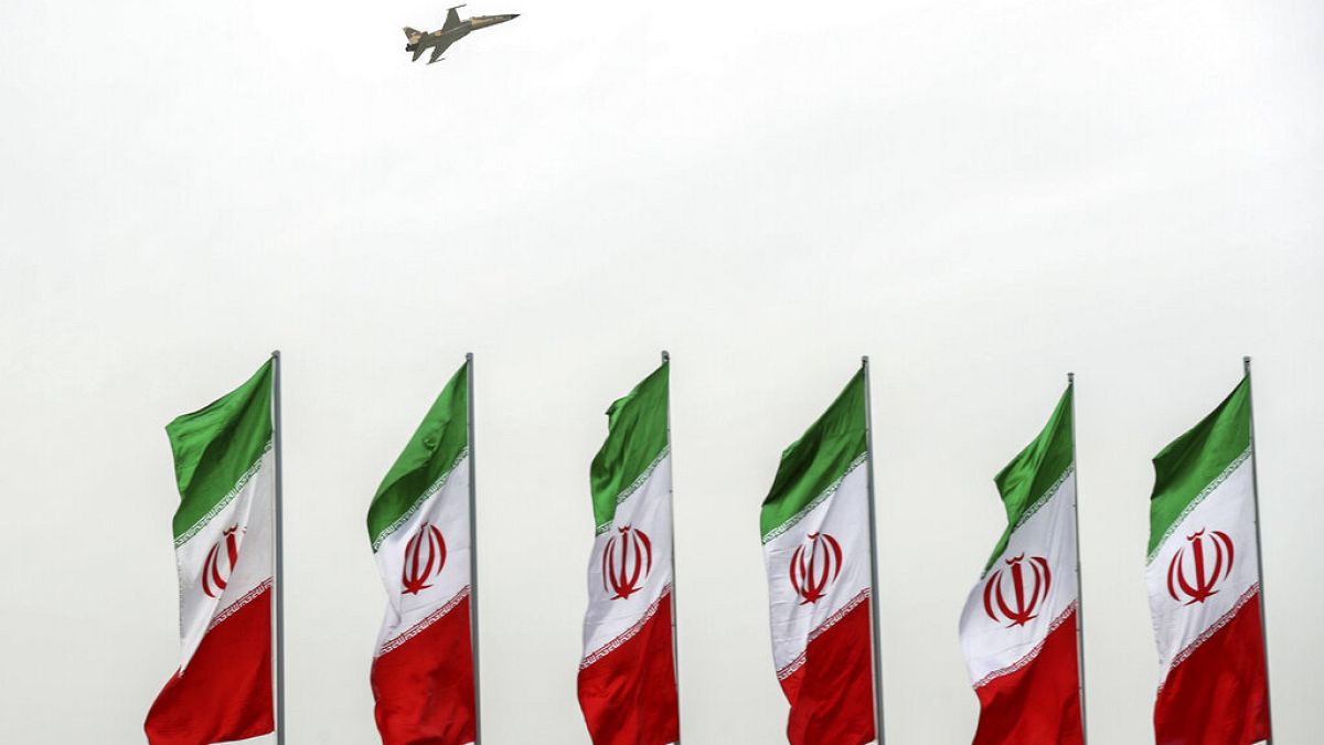 Ein Kampfjet fliegt während einer Militärparade in Teheran über iranischen Flaggen 