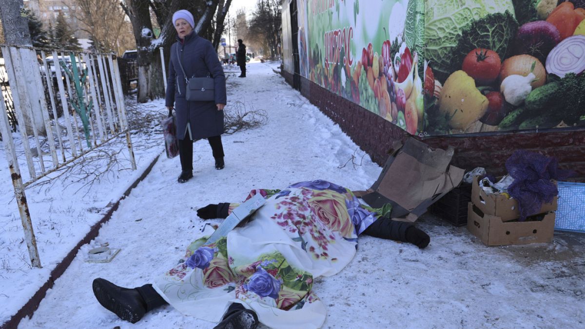 A woman walks past a body of a victim killed during the shelling that Russian officials in Donetsk 21/1/2024.