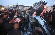 Палестинцы окружили автомобиль, пострадавший от израильского авиаудара в Рафахе, сектор Газа, суббота, 20 января 2024 года.