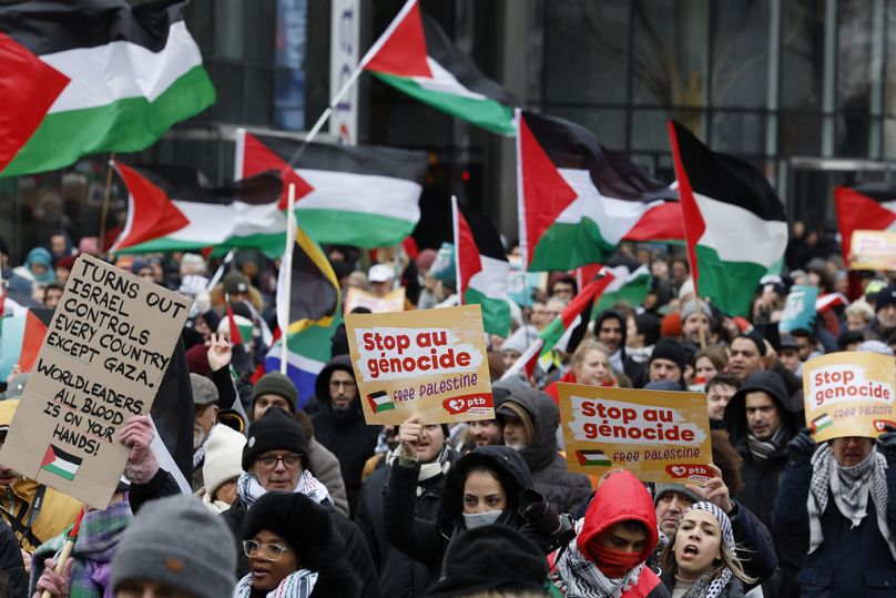 Demonstrators hold signs and wave flags during a pro-Palestinian rally in Brussels, Sunday, Jan 21, 2024.