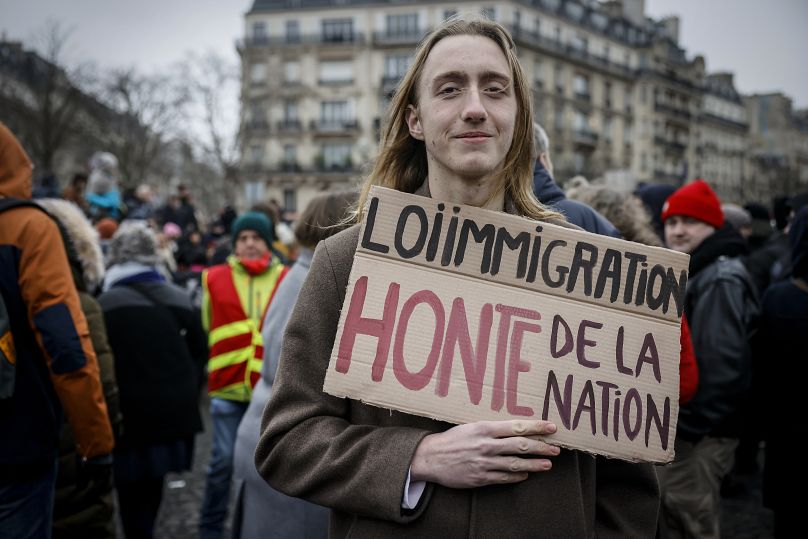 Участник акции против закона об иммиграции в Париже с транспарантом: "Закон об иммиграции - позор нации", 21 января 2024 г.