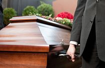 A man carries a coffin. 
