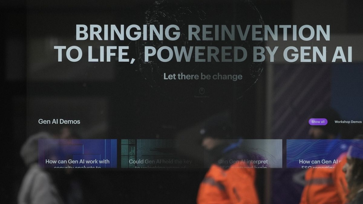 People reflected in a window of a building at the Davos Promenade with a slogan about AI alongside the World Economic Forum in Davos, Switzerland, Thursday, Jan. 18, 2024. 