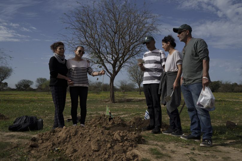 Friends and relatives pray before planting a tree in memory of person who was killed on Oct. 7 in a cross-border attack by Hamas at the Nova music festival.