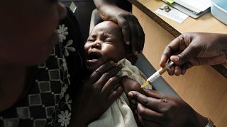 Una madre sostiene a su bebé que recibe una nueva vacuna contra la malaria como parte de un ensayo en Kenia.
