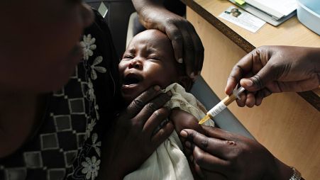 Uma mãe segura o seu bebé que recebe uma nova vacina contra a malária no âmbito de um ensaio no Quénia.