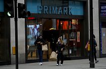 Women carry shopping bags as they leave a Primark clothes store on Oxford Street. 