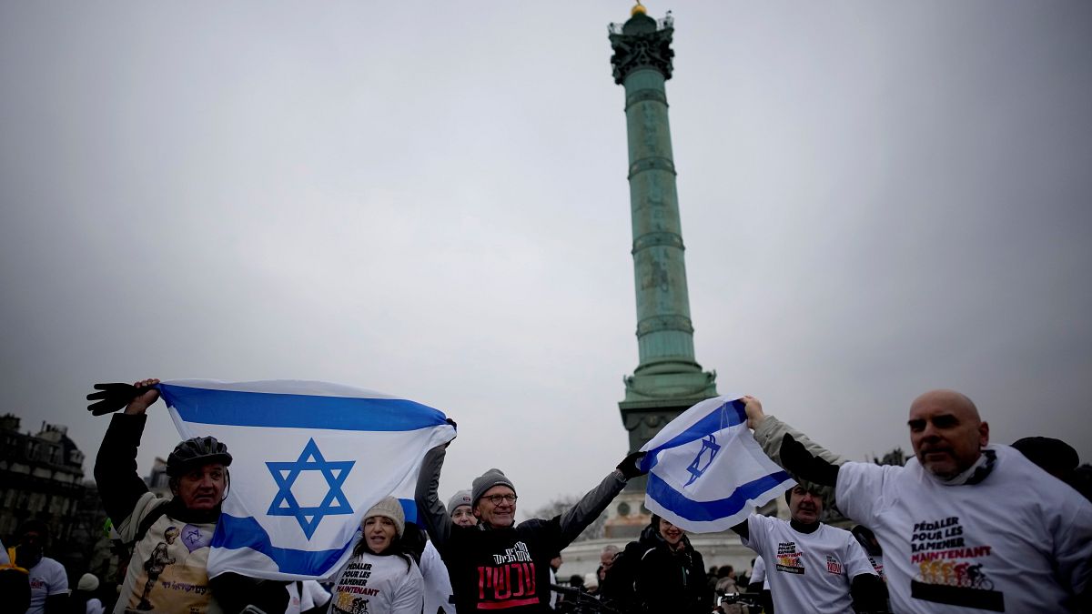 متظاهرون يحملون الأعلام الإسرائيلية خلال مسيرة لإحياء مرور 100 يوم على هجوم 7 أكتوبر، في باريس