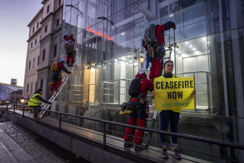 Greenpeace activists prepare to climb hang and hang an illustration by U.S. visual artist Shepard Fairey "Obey" as a protest against the war in Gaza.