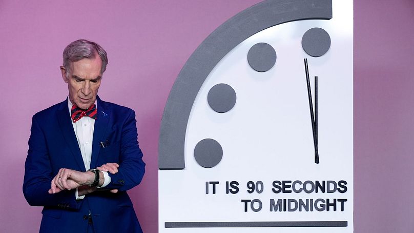 Science educator Bill Nye, looks at his watch next to the "Doomsday Clock," shortly before the Bulletin of the Atomic Scientists announces the latest decision