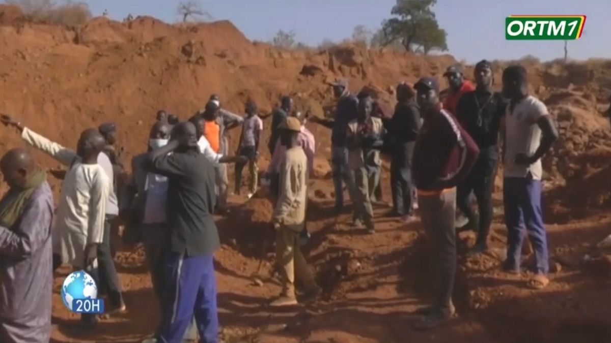 Un grupo de malienses observan el área donde se produjo el colapso de una mina de oro, enero de 2024.