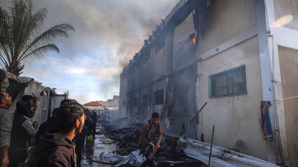 فلسطيني يحاول إخماد الحرائق التي اندلعت في مبنى تابعة للأونروا