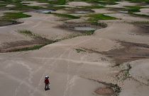 A resident of a riverside community carries food and water distributed due to the ongoing drought in Careiro da Varzea, Amazonas state, Brazil, 24 October 2023.