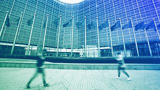 European Union flags wave in the wind as pedestrians walk by EU headquarters in Brussels, November 2023
